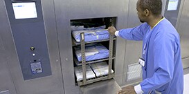 Pracownik centralnej sterylizacji ładujący wsad z instrumentarium do sterlizatora
