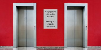 Czerwona ściana z białą naklejką, między dwoma windami.
