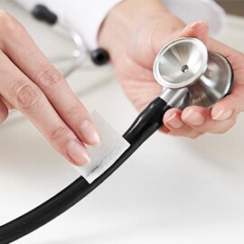 Dłonie czyszczące przewód stetoskopu Littmann przy użyciu czyścika nasączonego alkoholem.