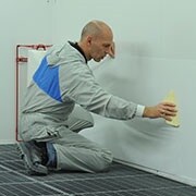 Mężczyzna nakładający materiał ochronny Dirt Trap na ścianę za pomocą rakli