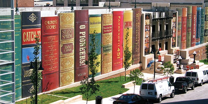Biblioteka oklejona z zewnątrz folią graficzną przedstawiającą rząd gigantycznych książek.
