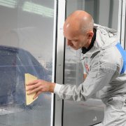 Mężczyzna nakładający na okno folię ochronną Dirt Trap za pomocą rakli