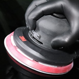 Obraz dłoni w czarnej rękawiczce z elektryczną i pneumatyczną szlifierką mimośrodową 3M™
