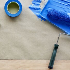 Taśma malarska ScotchBlue™ obok pędzla pokrytego niebieską farbą