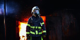 strażacy przechodzący przez zadymiony budynek
