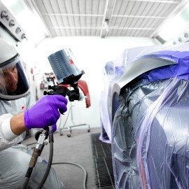 Lakiernik natryskujący powłokę na samochód za pomocą pistoletu natryskowego 3M