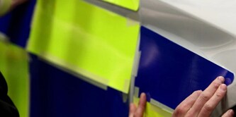 Osoba zakładająca folię odblaskową na radiowóz
