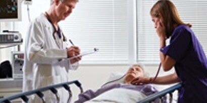 Lekarz koło łóżka pacjenta, pielęgniarka używająca stetoskopu

