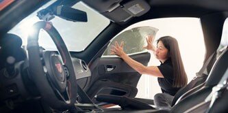 Kobieta nakładająca folię okienną na auto
