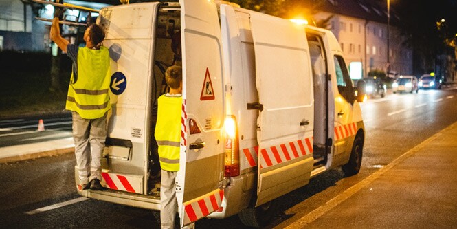 Samochód dostawczy zaparkowany na poboczu drogi z widocznymi oznaczeniami
