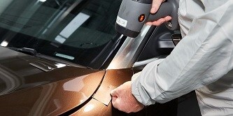 Mężczyzna porównujący próbnik kolorów z powierzchnią lakieru samochodowego
