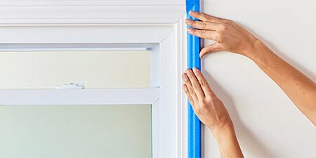 Ręce pokazujące, jak docisnąć dokładnie taśmę do powierzchni
