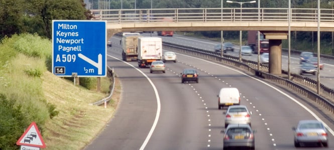 Ruch na autostradzie z widocznym dużym znakiem drogowym
