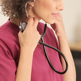 Pielęgniarka wkładająca oliwki Stetoskopu 3M Littmann Classic III do uszu.