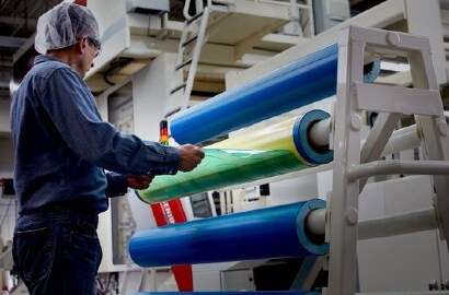 Zdjęcie pracownika zdejmującego płytę fotopolimerową z taśmy fleksograficznej na cylindrze
