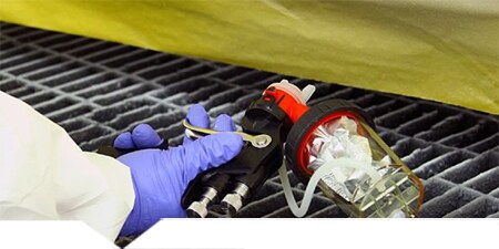 Technik używający pistoletu 3M Accuspray do nakładania powłoki ochronnej
